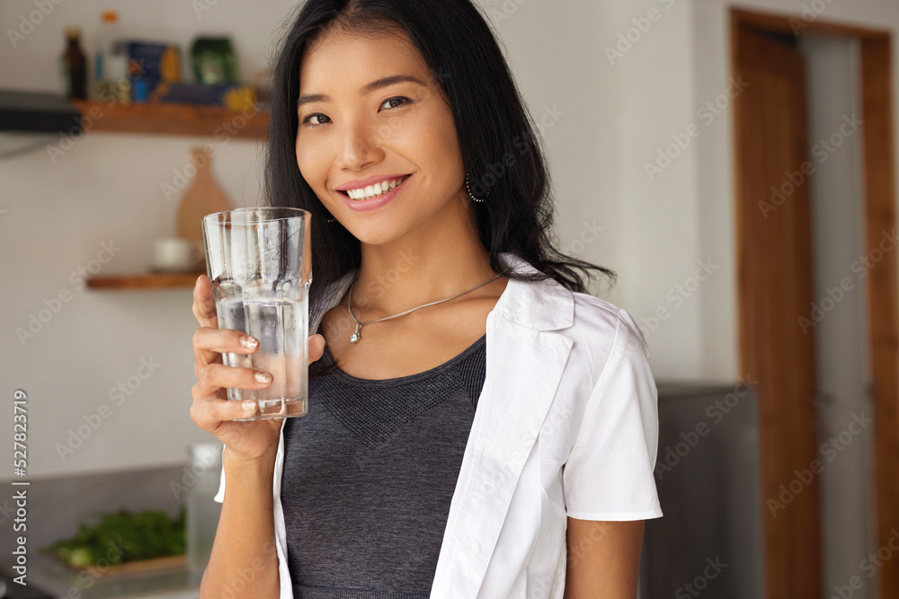 Happy Young Woman Holding Glass Of Fresh Water In White Kitchen Portrait. Beautiful Smiling Girl Drinking Pure Mineral Water In Morning At Home Happy Young Woman Holding Glass Of Fresh Water In White Kitchen Portrait. Beautiful Smiling Girl Drinking Pure Mineral Water In Morning At Home