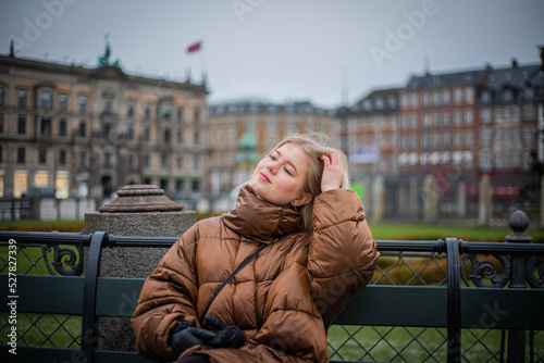 Photography A girl sitting on a bench breathes in the fresh air and relaxes in Copenhagen during winter