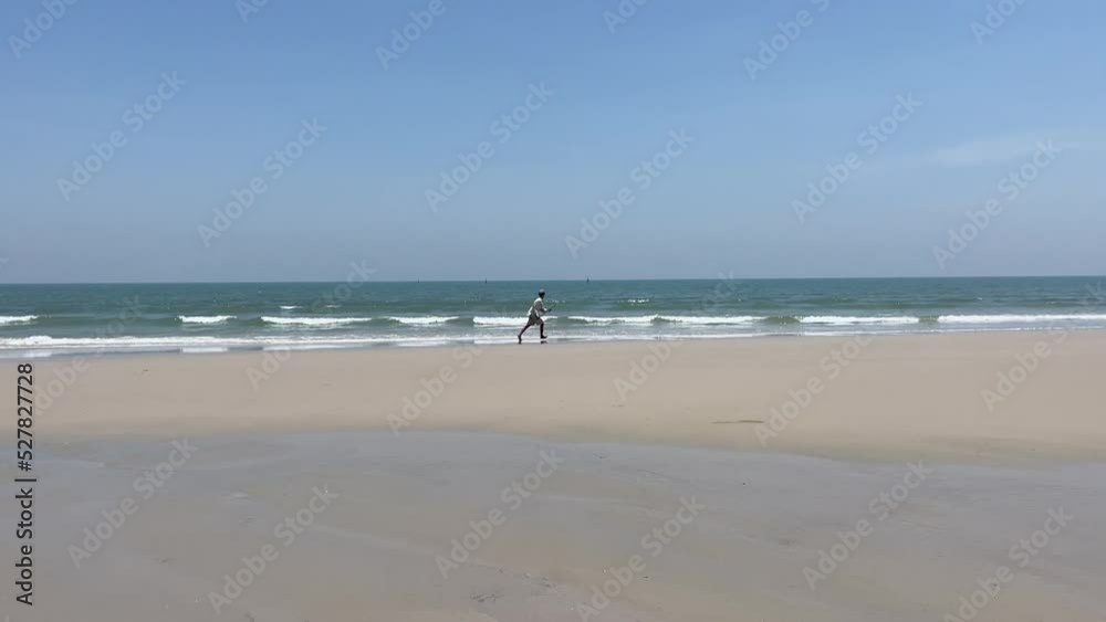 Beachfront landscape view on a sunny day. Unrecognized man playing surfboard and fail. Blue sky, wave and sand at Hua Hin beach Beachfront landscape view on a sunny day. Unrecognized man playing surfboard and fail. Blue sky, wave and sand at Hua Hin beach