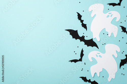 Halloween concept. Top view photo of ghost bat silhouettes and black confetti on isolated pastel blue background with copyspace