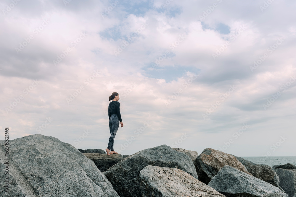 Sporty, fit woman standing on rocks looking out to sea, getting away from it all. Sporty, fit woman standing on rocks looking out to sea, getting away from it all.