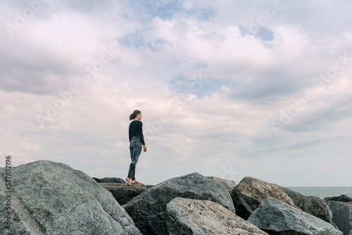 Sporty  fit woman standing on rocks looking out to sea  getting away from it all.
