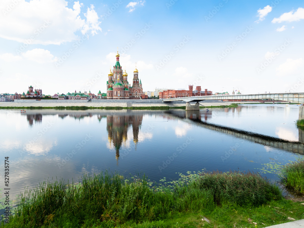 Malaya Kokshaga river and view of Voskresenskaya embankment with Cathedral of the Annunciation of the Blessed Virgin Mary near Theater bridge in Yoshkar-ola city in summer