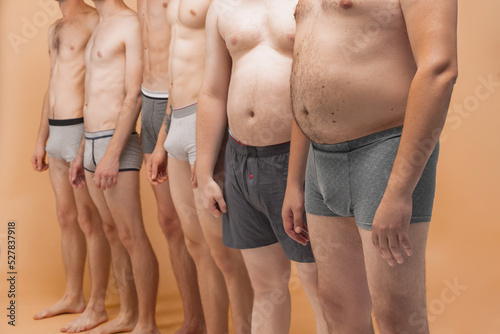 Cropped image of male bodies in boxers panties standing together at studio photo shoot. Fun, joy, body positive and creativity photo