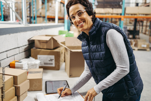 Happy warehouse manager writing a packing list