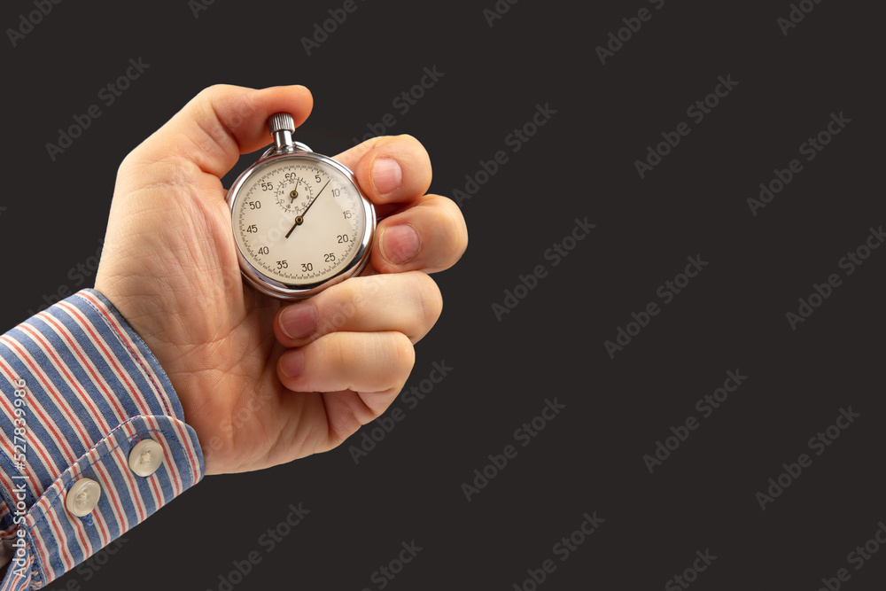hand with a mechanical analog stopwatch on a dark background. Time part precision. Measurement of the speed interval hand with a mechanical analog stopwatch on a dark background. Time part precision. Measurement of the speed interval