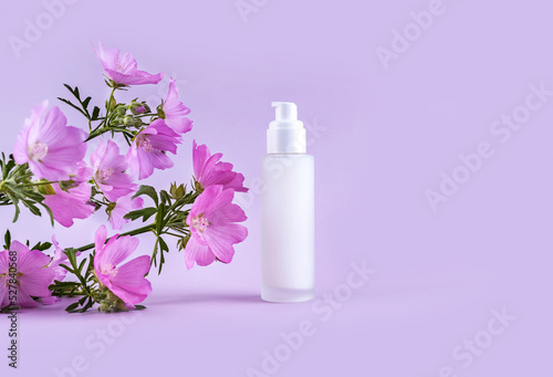  bottle for cosmetics and flowers on a purple background