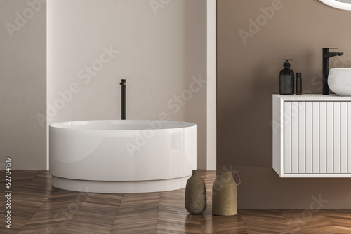 Beautiful oval bathtub wiht black faucet standing on parquet in modern bathroom. 