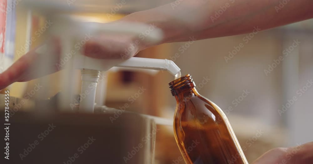 Close Up Of Woman Refilling Glass Bottle With Liquid Soap In Sustainable Zero Waste Plastic Free Store