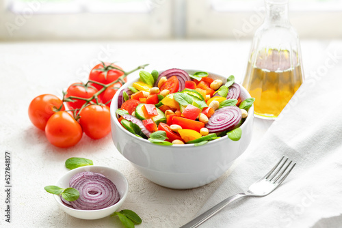 Summer salad with cherry tomatoes, cucumber, bell pepper, onion, basil and peanuts on windowsill. Summer diet salad concept. 