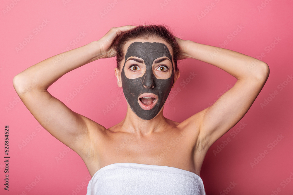 surprised young woman with a mask on her face, ties her hair, home care