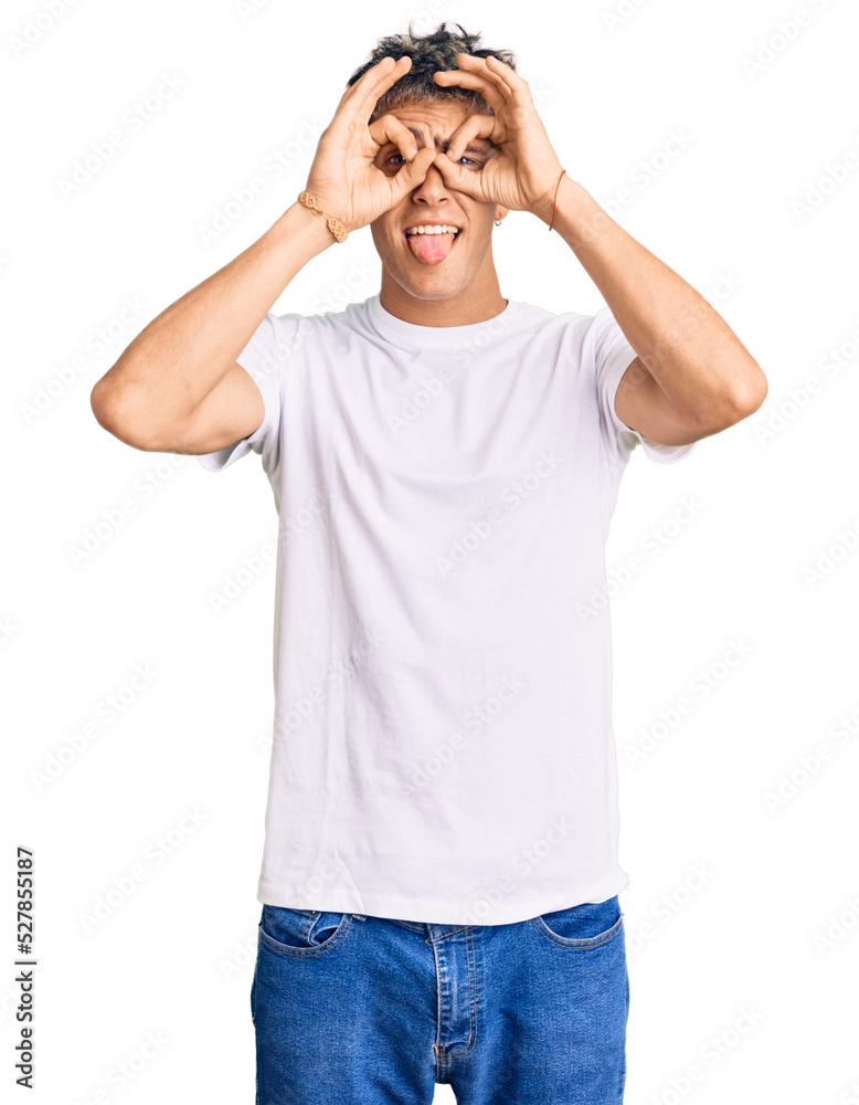 Young handsome man wearing casual white tshirt doing ok gesture like binoculars sticking tongue out, eyes looking through fingers. crazy expression. Young handsome man wearing casual white tshirt doing ok gesture like binoculars sticking tongue out, eyes looking through fingers. crazy expression.