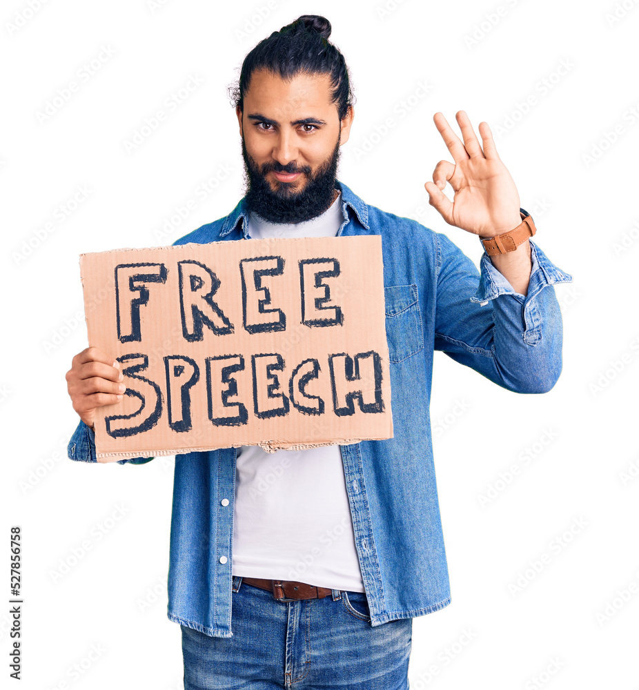 Young arab man holding free speech banner doing ok sign with fingers, smiling friendly gesturing excellent symbol Young arab man holding free speech banner doing ok sign with fingers, smiling friendly gesturing excellent symbol