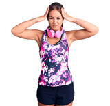 Young beautiful hispanic woman wearing gym clothes and using headphones suffering from headache desperate and stressed because pain and migraine. hands on head.