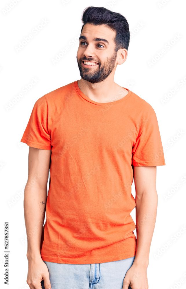Fototapeta premium Young handsome man with beard wearing casual t-shirt looking away to side with smile on face, natural expression. laughing confident.