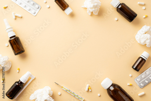 Disease concept. Top view photo of remedy transparent brown bottles pills blisters thermometer and crumpled paper napkins on isolated beige background with copyspace in the middle
