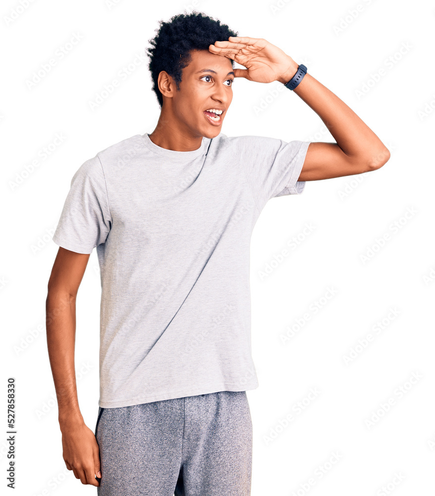 Young african american man wearing casual clothes very happy and smiling looking far away with hand over head. searching concept. Young african american man wearing casual clothes very happy and smiling looking far away with hand over head. searching concept.