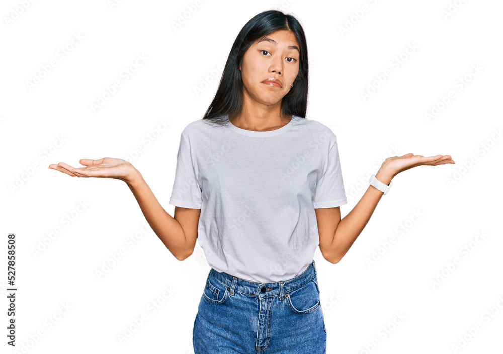 Beautiful young asian woman wearing casual white t shirt clueless and confused expression with arms and hands raised. doubt concept. Beautiful young asian woman wearing casual white t shirt clueless and confused expression with arms and hands raised. doubt concept.