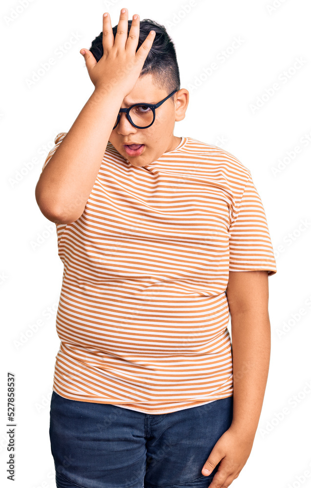 Little boy kid wearing casual clothes and glasses surprised with hand on head for mistake, remember error. forgot, bad memory concept. Little boy kid wearing casual clothes and glasses surprised with hand on head for mistake, remember error. forgot, bad memory concept.