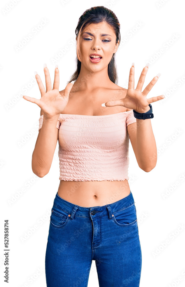 Young beautiful woman wearing casual clothes afraid and terrified with fear expression stop gesture with hands, shouting in shock. panic concept. Young beautiful woman wearing casual clothes afraid and terrified with fear expression stop gesture with hands, shouting in shock. panic concept.