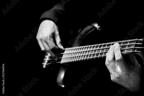 фотографія black and white musician hands playing electric bass guitar on black background