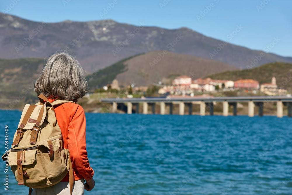 Woman backpacker. Lake and mountain landscape. Riano village, Spain