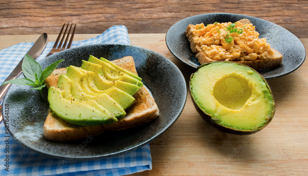 Healthy avocado toasts for breakfast. sliced avocado, salt and pepper with scrambled eggs on toasts. Whole food concept.