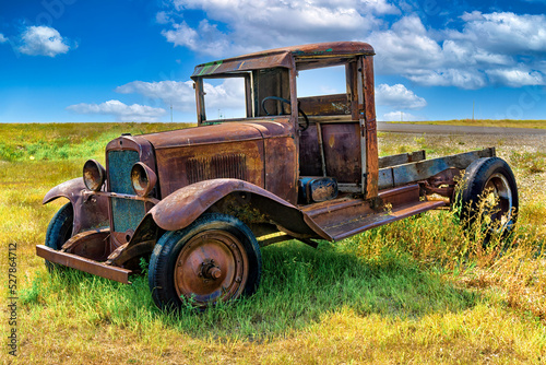 A rusty old truck in a field, abandoned. 