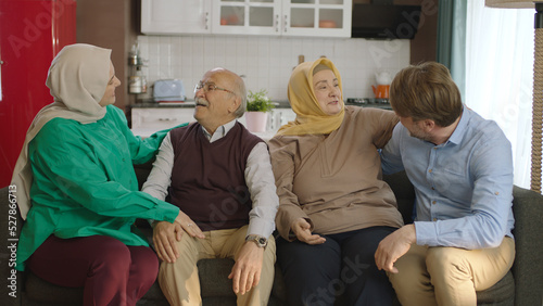 A Muslim Turkish family visits their living room for Eid. Eid Mubarak celebration moment, big family photo on sofa wearing traditional festive clothes. Happy Muslim family. Traditional Muslim customs. photo