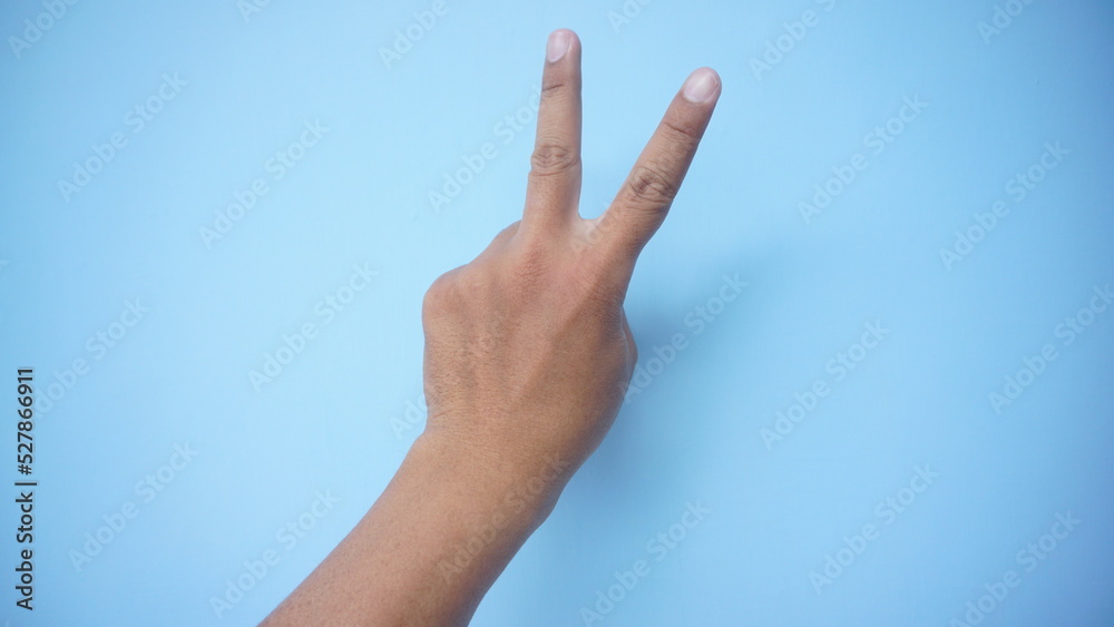 Peace sign gesture made by child on blue background. World peace concept Peace sign gesture made by child on blue background. World peace concept