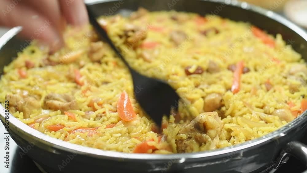 The cook stirs the freshly cooked chicken pilaf.
The cook stirs the freshly cooked chicken pilaf.