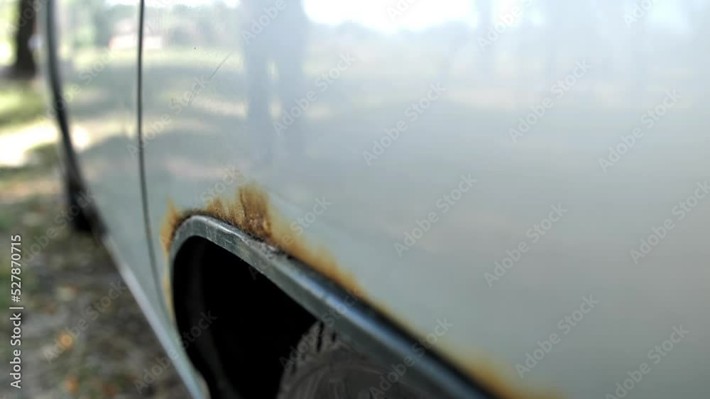 Rusty rear fender of a car. Rotten upholstery and peeling paint on top. A car requiring repair and welding of parts of the hull skin.
