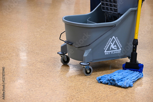 Microfiber mop and double bucket on shiny floor. Custodial activities. Floor maintenance in public building