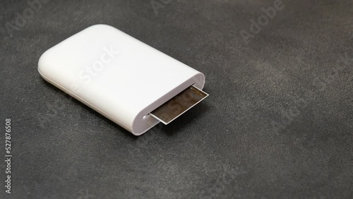 Proccess of printing photo with portable printer. Wireless mini printer for smartphones. Small prints for a photo album