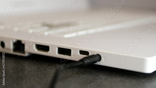 A man inserts a cable mini jack to the port laptop - connecting and disconnecting device into computer /  connection headphones with microphone into port mini jack in laptop