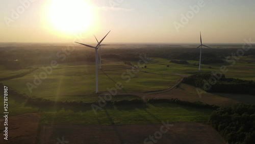 Green energy, electricity concept. Aerial cinematic drone panoramic shot of windmills and electricity wind turbines farm. Summer sunset sunny golden hours evening time. Panoramic European nature view