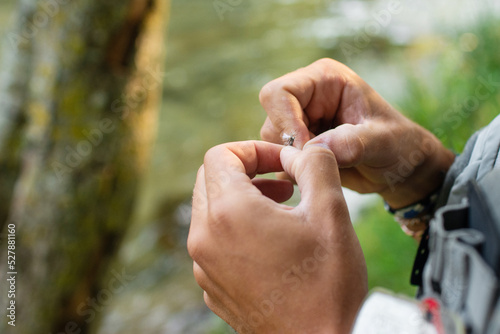 Anonymous fisherman preparing hooks for river fishing photo