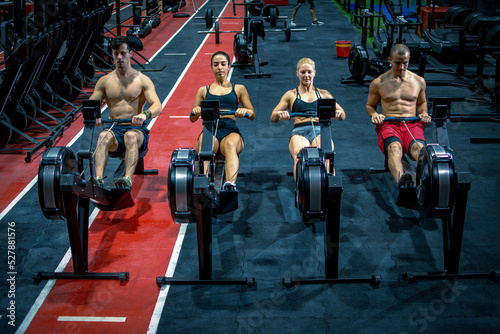 Group of sporty people working out on the rowing machines at the gym.