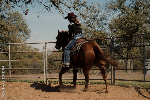 Cowgirl horseback riding for horse training in round pen outdoors, western lifestyle. photo