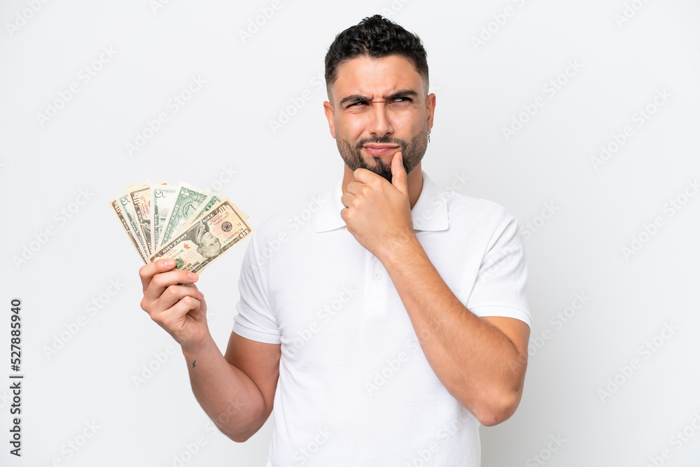 Young Arab man taking a lot of money isolated on white background having doubts and thinking Young Arab man taking a lot of money isolated on white background having doubts and thinking
