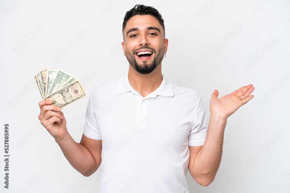 Young Arab man taking a lot of money isolated on white background with shocked facial expression Young Arab man taking a lot of money isolated on white background with shocked facial expression