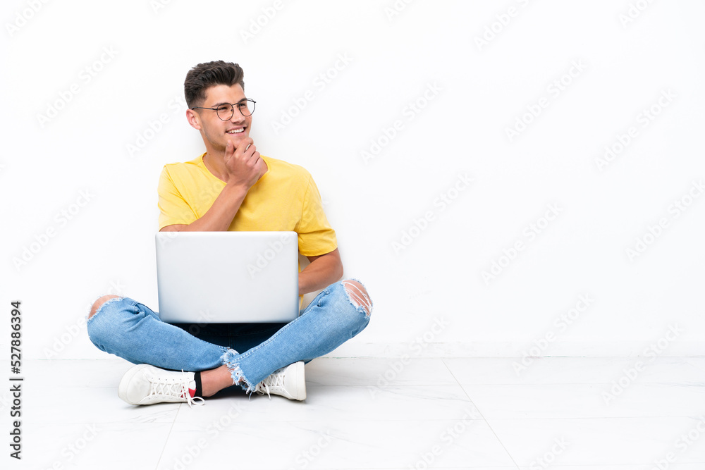 Young man sitting on the floor isolated on white background looking to the side Young man sitting on the floor isolated on white background looking to the side