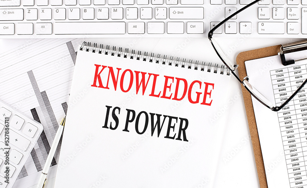 Text KNOWLEDGE IS POWER on Office desk table with keyboard, notepad and analysis chart on white background. Text KNOWLEDGE IS POWER on Office desk table with keyboard, notepad and analysis chart on white background.
