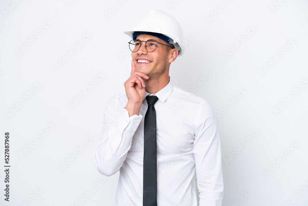 Young architect caucasian man with helmet and holding blueprints isolated on white background thinking an idea while looking up Young architect caucasian man with helmet and holding blueprints isolated on white background thinking an idea while looking up