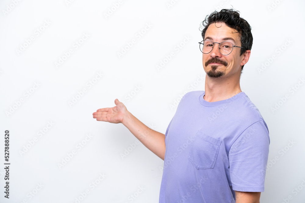 Young man with moustache isolated on white background extending hands to the side for inviting to come Young man with moustache isolated on white background extending hands to the side for inviting to come