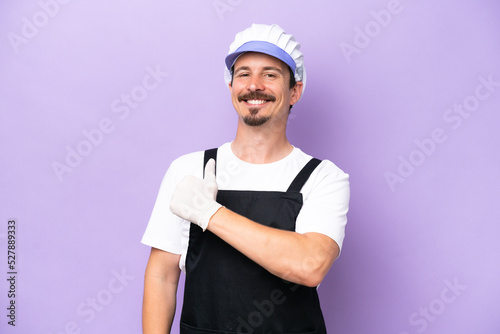 Fishmonger man wearing an apron isolated on purple background giving a thumbs up gesture
