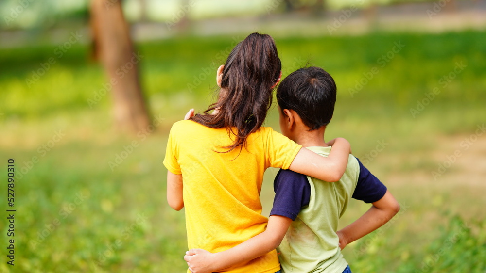 two siblings standing together in the park two siblings standing together in the park