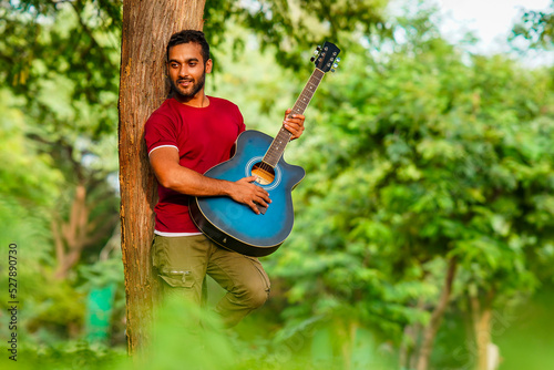 portrait of A boy clinging to a tree is playing the guitar