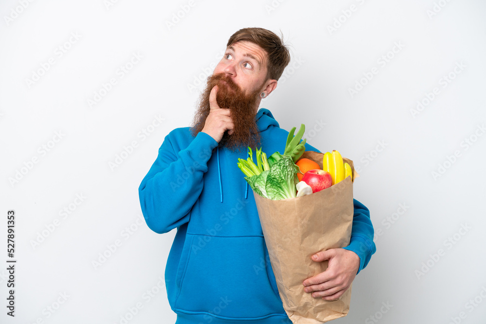 Redhead man with beard holding a grocery shopping bag isolated on white background and looking up Redhead man with beard holding a grocery shopping bag isolated on white background and looking up