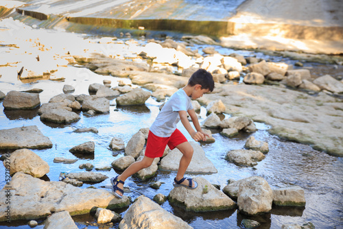 child crosses a river by stepping on stones to avoid getting his feet wet